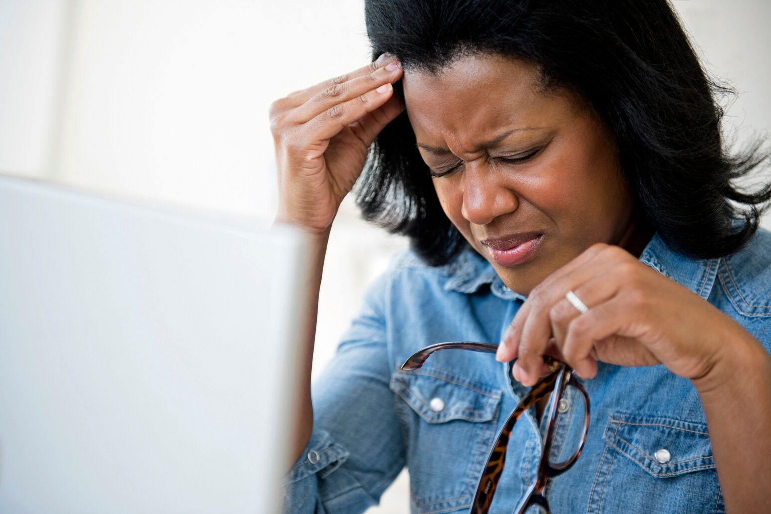 A black woman holds her head in pain. Henry Woo, MD, discusses Game of Thrones star Emilia Clarke's experience with brain aneurysms.
