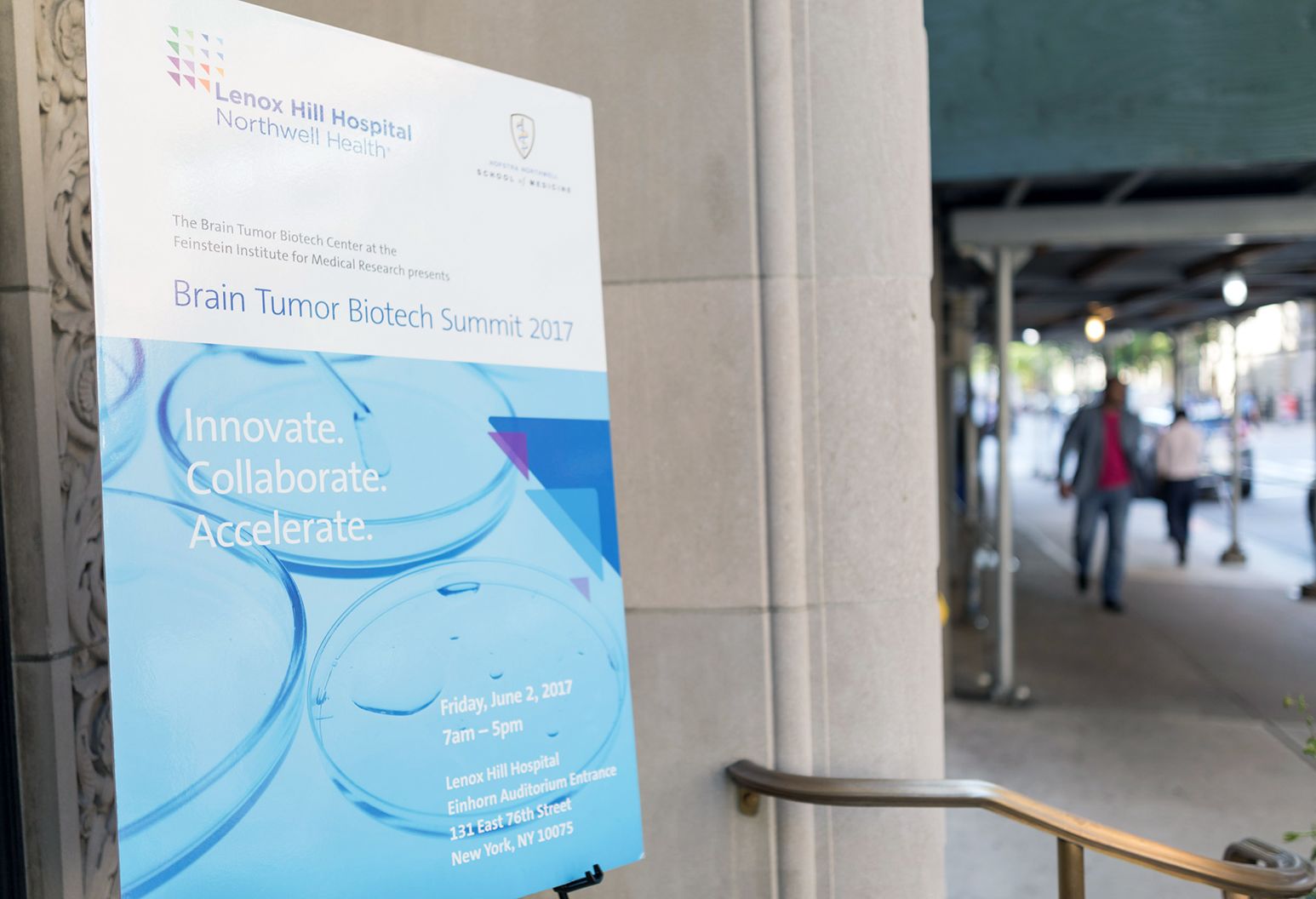 Sign promoting a conference is sitting on an easel outside a building entrance