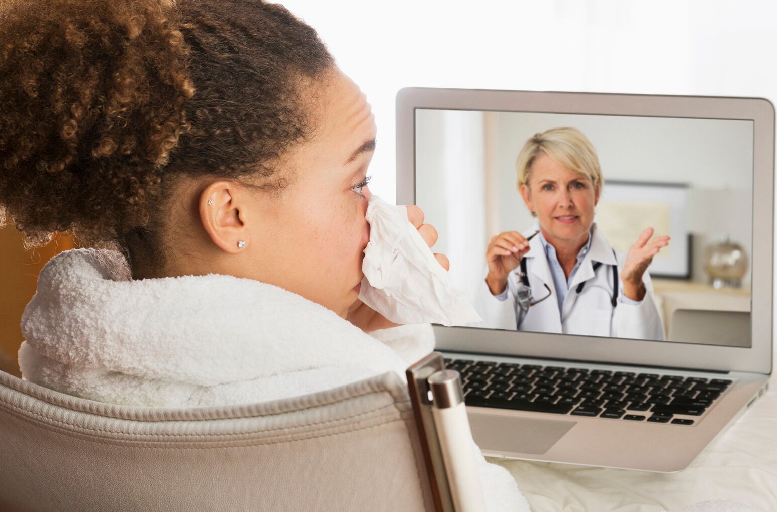 A sick woman talks to a doctor through a telehealth services device.