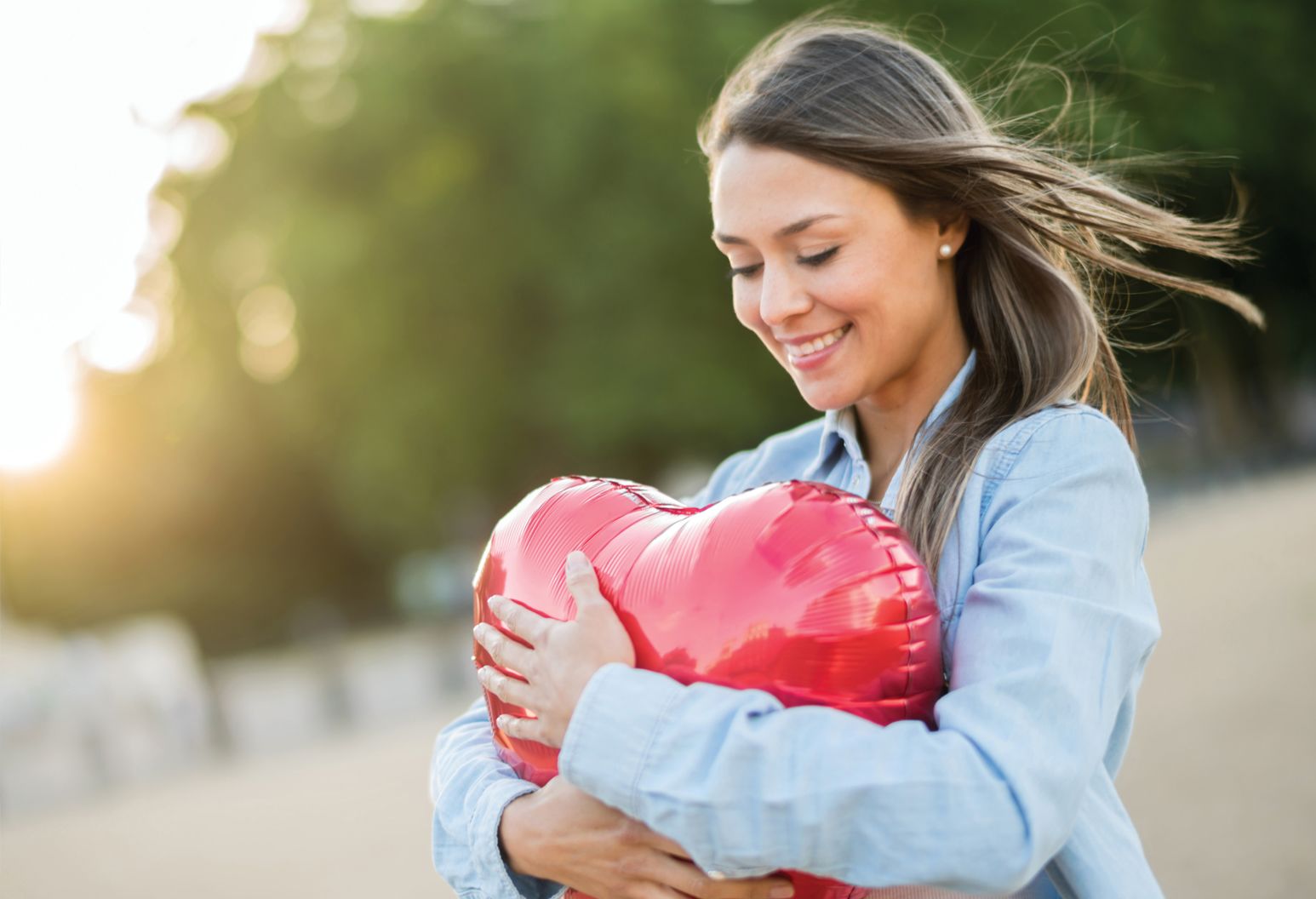 Woman embracing a heart shaped balloon.
