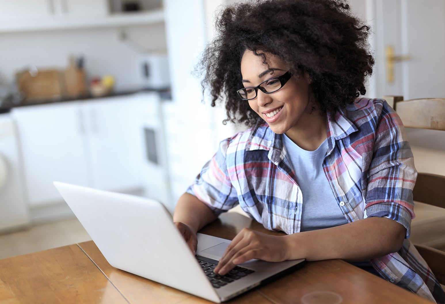 A woman gleefully surfs the web on her laptop with a smile on her face