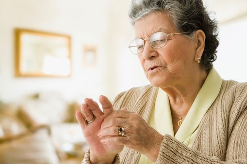 An elderly woman holds her hand