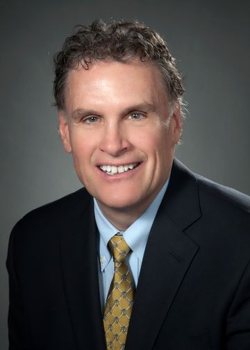 Terry Lynam headshot, wearing a gold tie and a robin's egg blue shirt