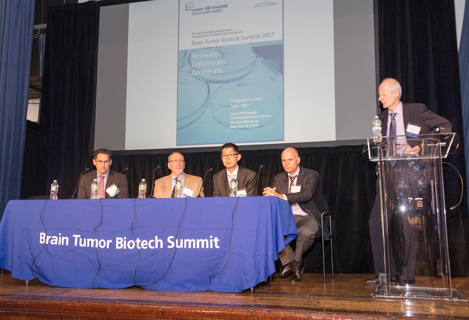 Panel of 5 professional men on stage at a conference