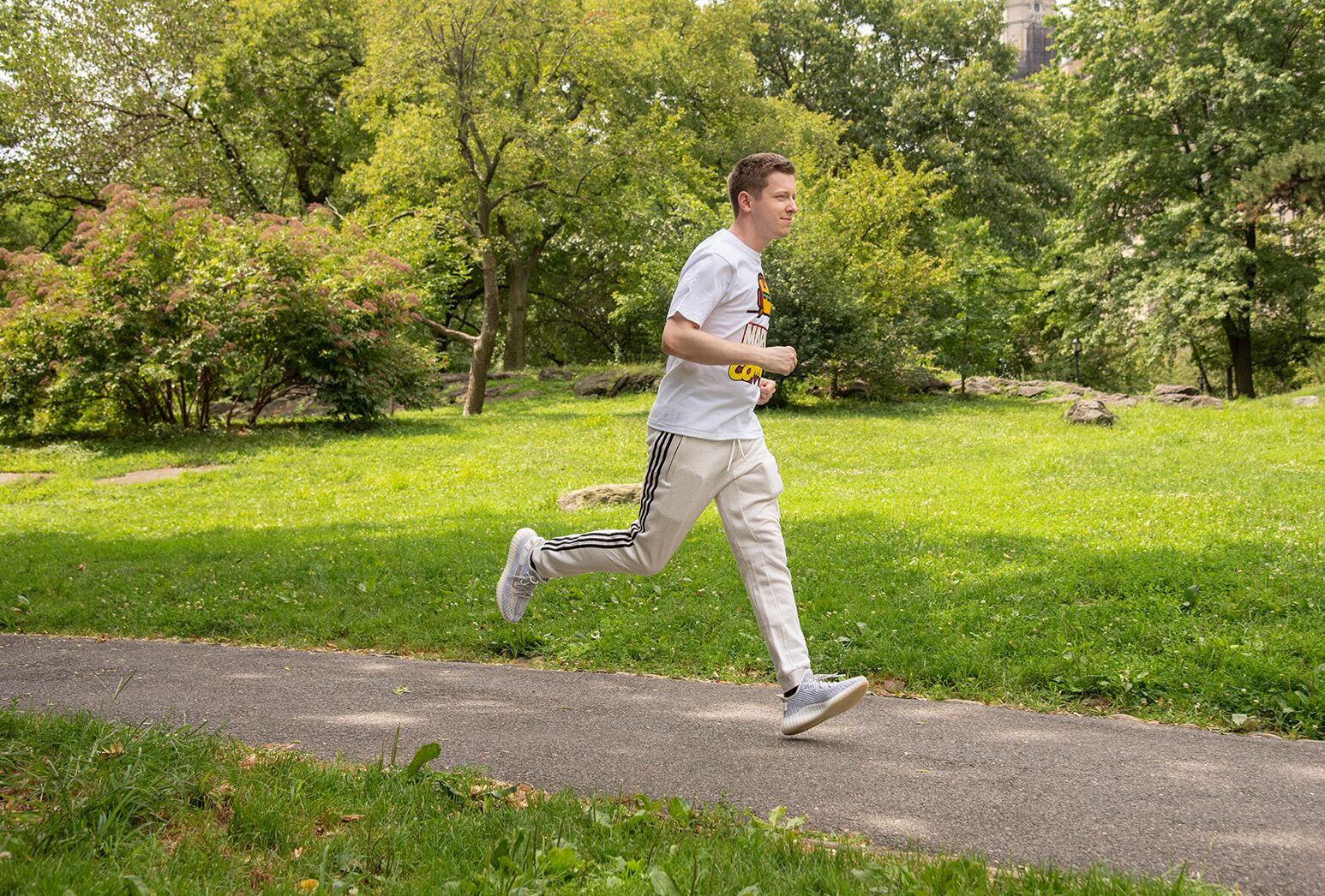 Young man who suffered a stroke at age 21 in white sweatpants and shirt running in Central Park