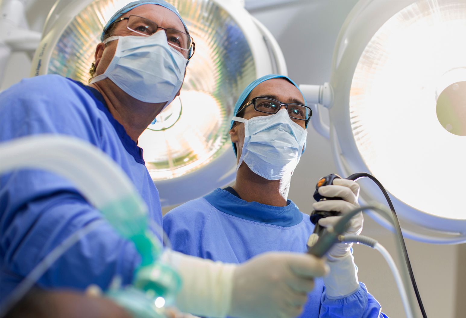 Two male physicians in surgical gear operating with robotic technology