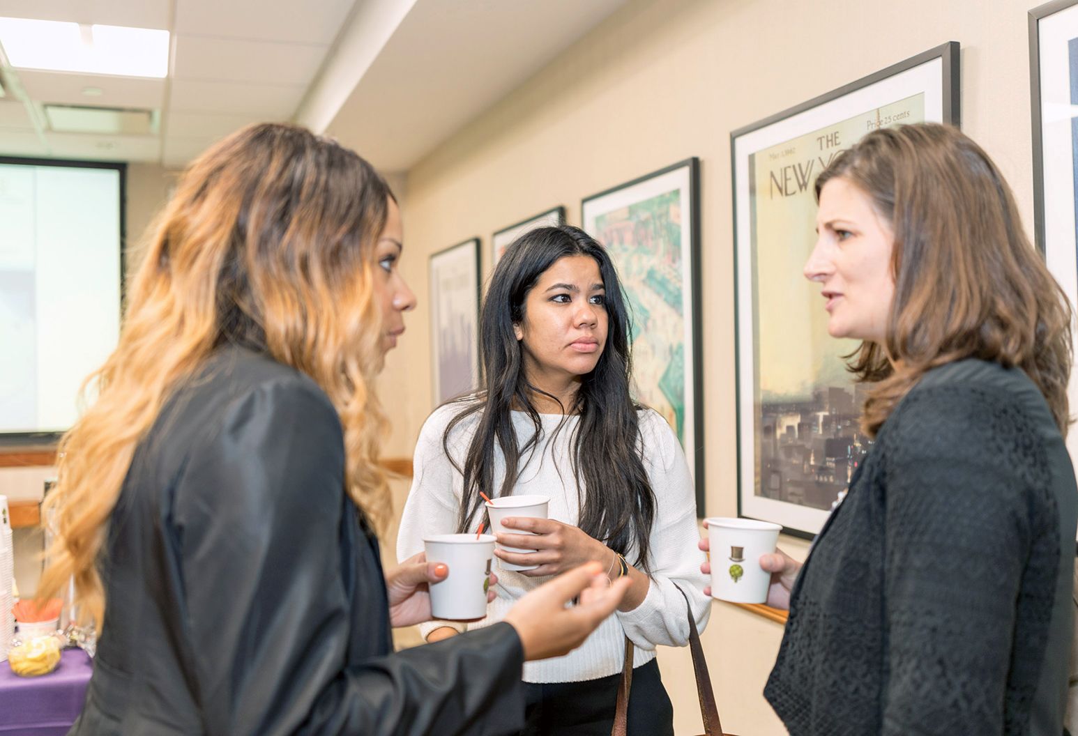 Three female professionals are talking in the hallway at a conference