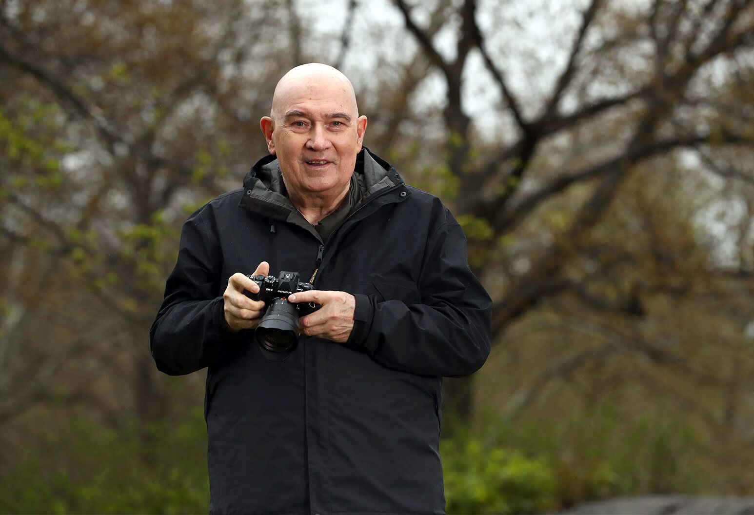 A man poses in the park with his professional camera.
