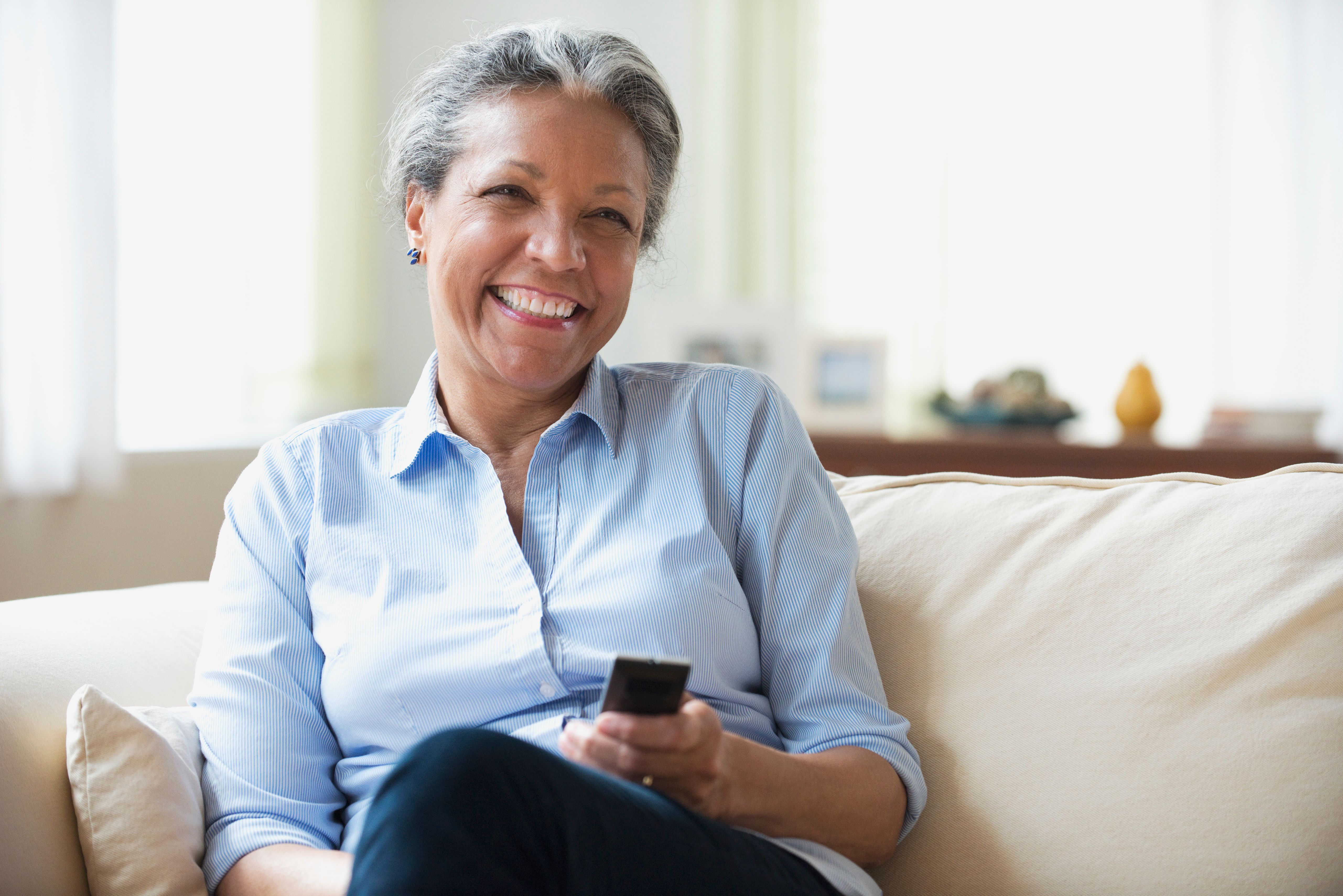 A woman holds a remote control and smiles