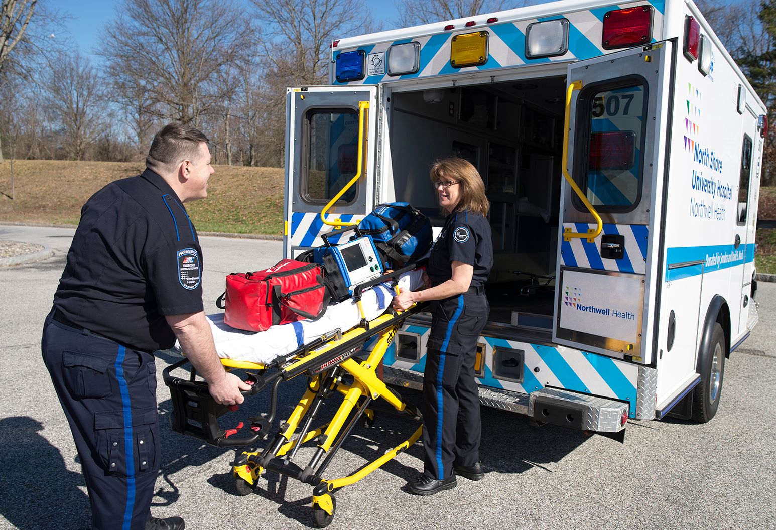 2 EMTs load a stretcher into the back of an ambulance.