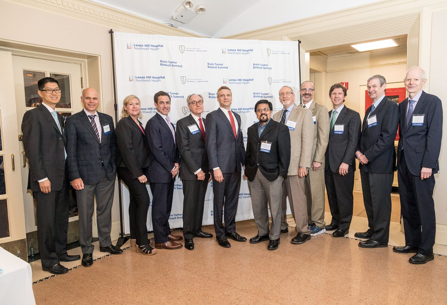 Group of twelve professionals, all wearing suits, stand together for a group photograph