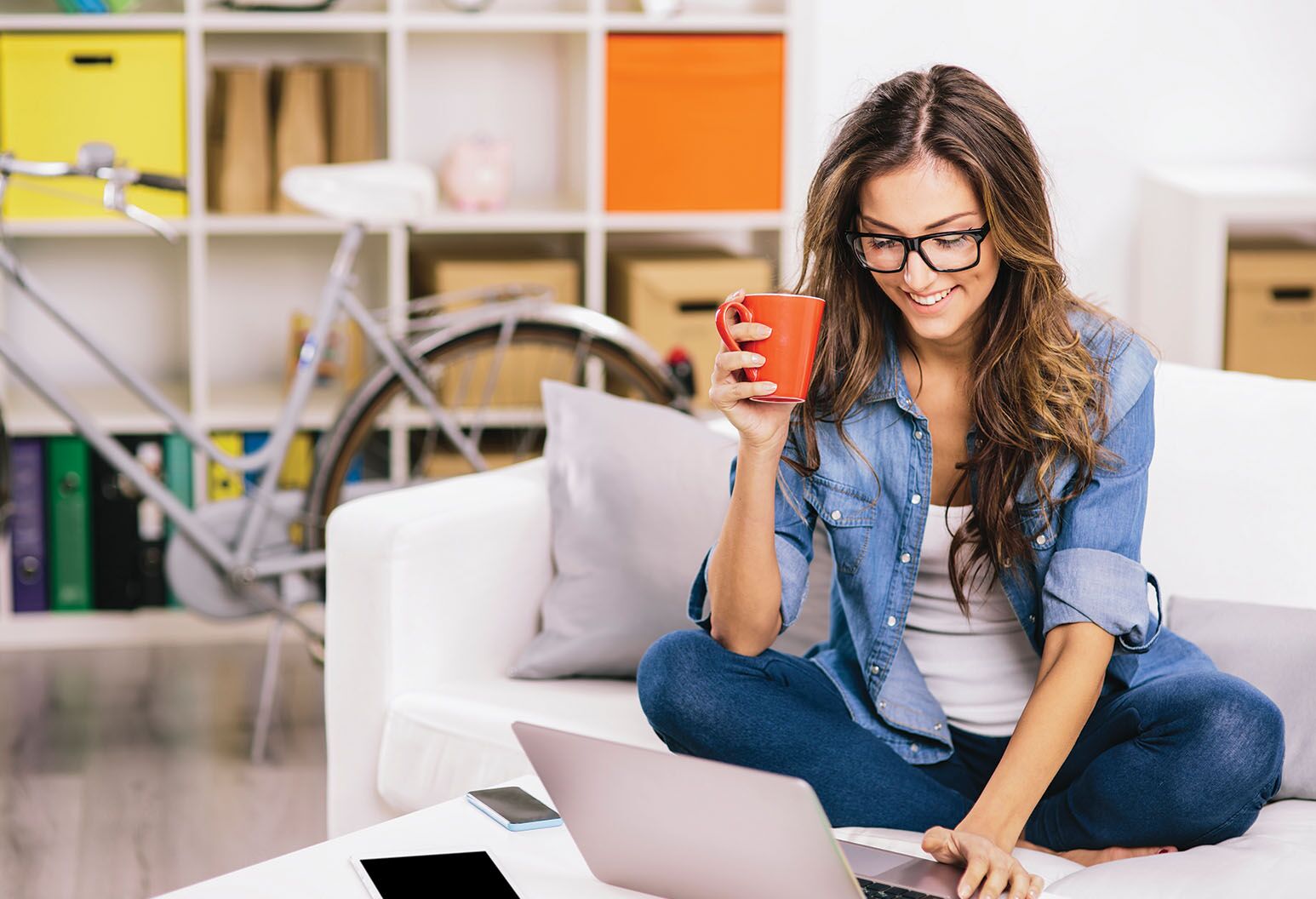 a women holding a coffee mug using a laptop