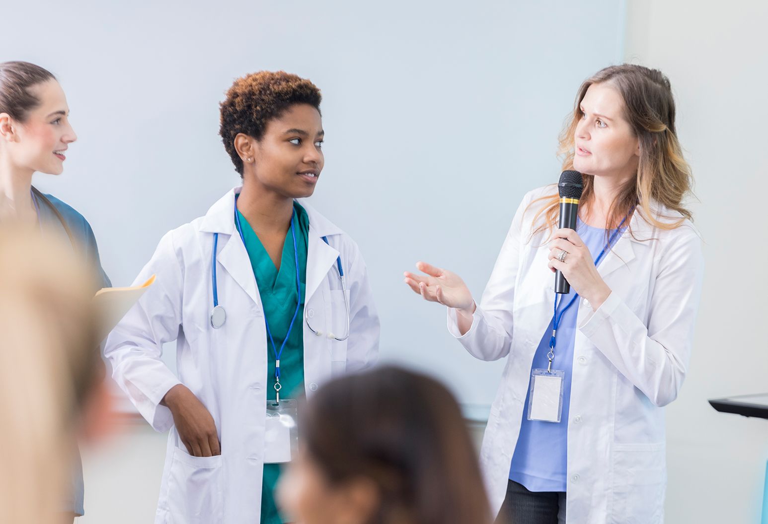 Three physicians standing in front of an audience speaking intelligently.