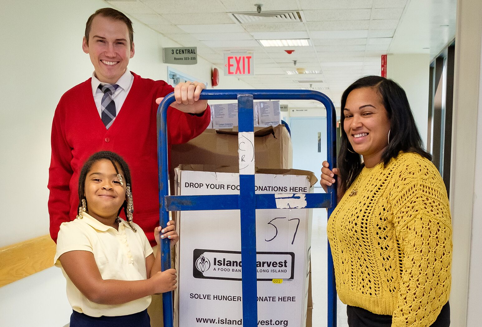 From left: Mr. Rogers look alike Chris Kind helps 2nd grade student Tianna Huggins and her mother Nistachia Belle, of Roosevelt, LI, load some of the food collected for Island Harvest into a waiting truck.