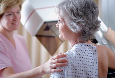 A middle aged woman wearing a nightgown getting mammogram
