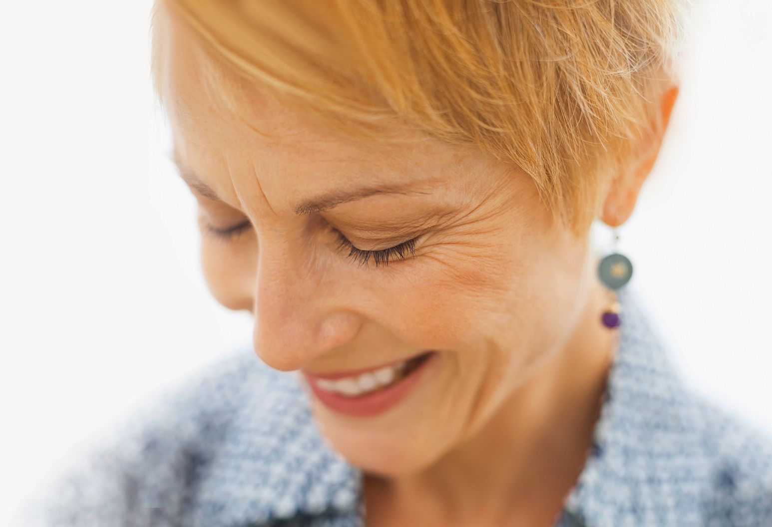 Mature woman smiling with head bent and eyes closed