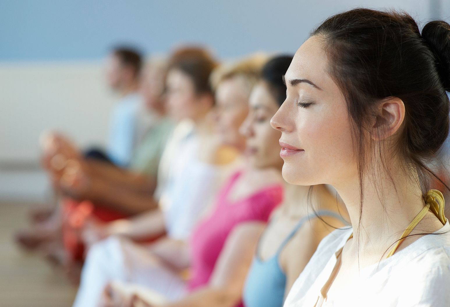 Row of woman with their eyes closed, doing yoga