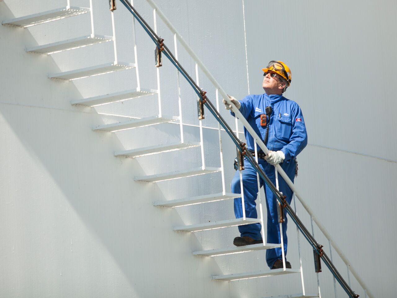 alt="refinery worker climbing staircase outside" alt="refinery worker climbing staircase outside"