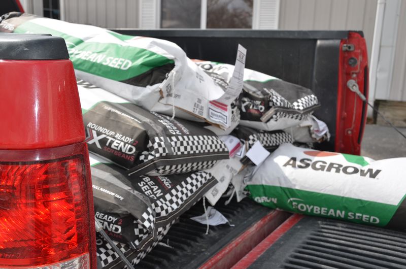 Farmer loading seed bags into pickup truck with seed dealer in Monroe City, MO. Seed delivery
